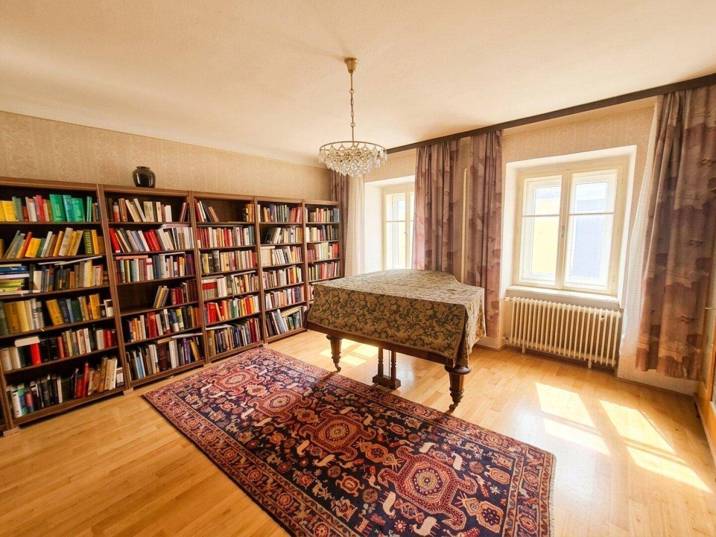 Elegante Bibliothek mit vielen Büchern, einem Klavier und Parkettboden.