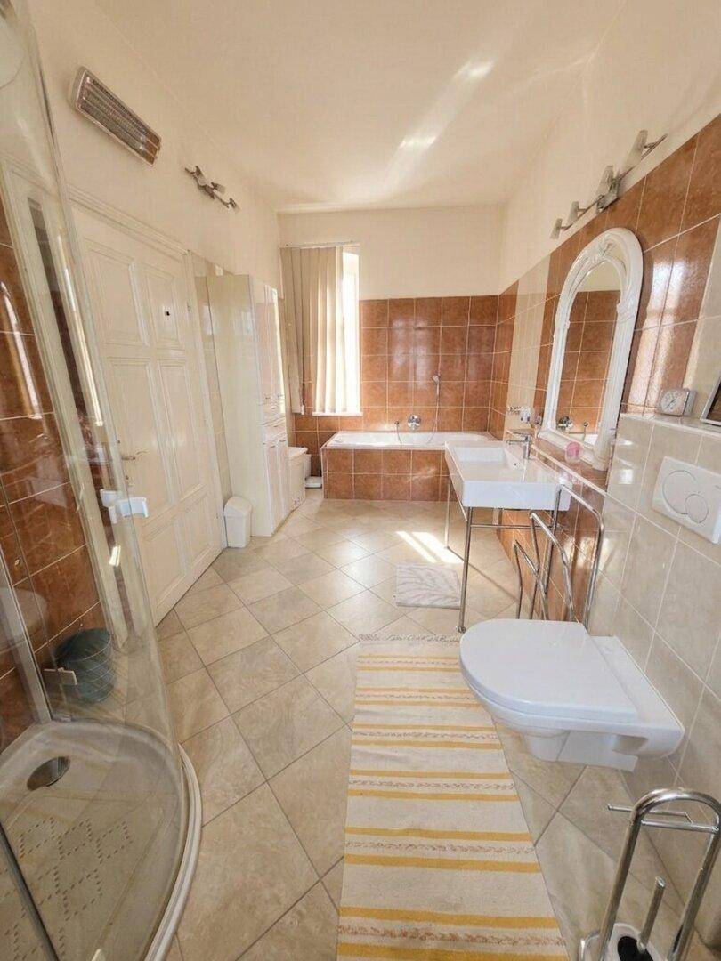 Geräumiges Badezimmer mit braunen Fliesen, Badewanne, Dusche und Doppelwaschbecken.