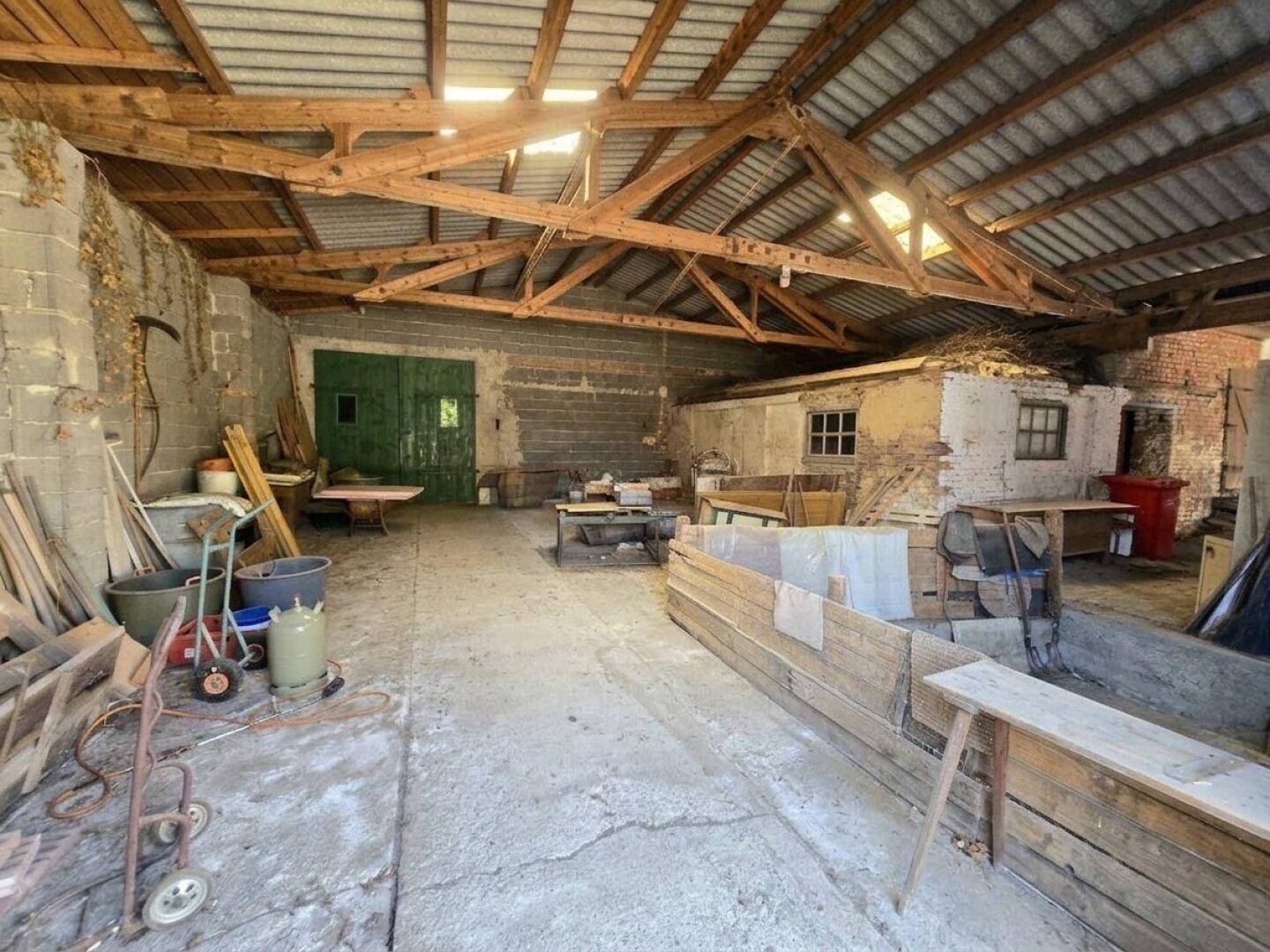 Geräumiger Werkstatt- oder Lagerbereich mit Holzdachkonstruktion und Betonboden.