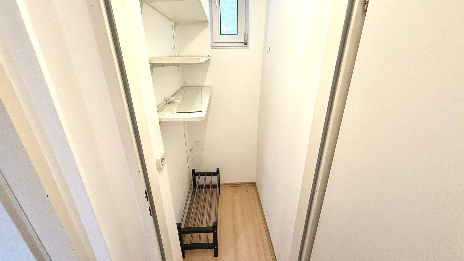 Heller Abstellraum mit Fenster, Regalen und Schuhregal, bietet praktischen Stauraum.