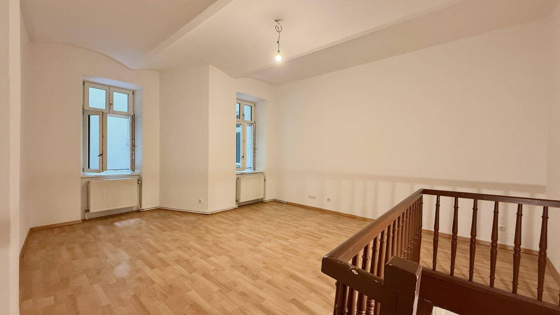 Leerer Raum mit Holzboden, weißen Wänden und zwei Fenstern, bereit zur individuellen Gestaltung.