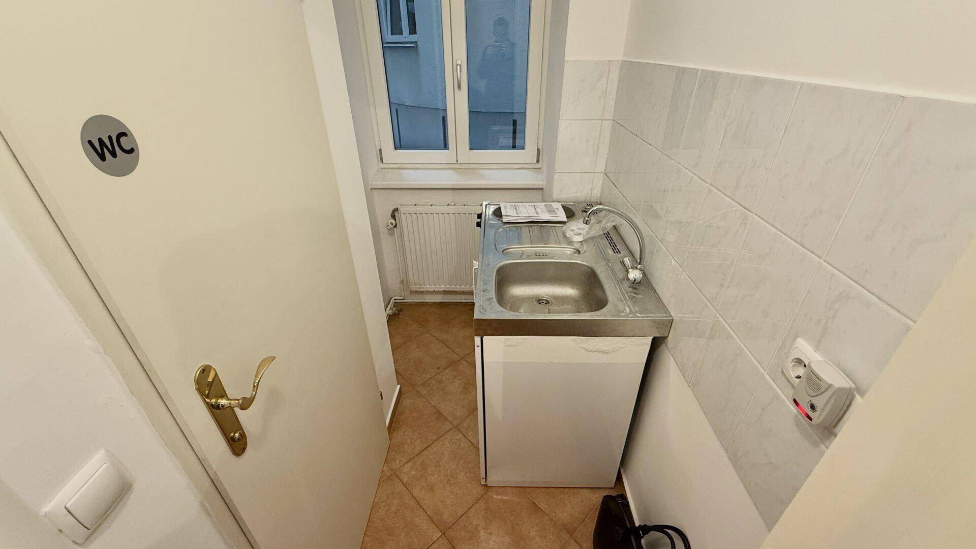 Kompakte Küchenzeile mit Spüle, Kochplatten und einem Fenster, praktisch und funktional.