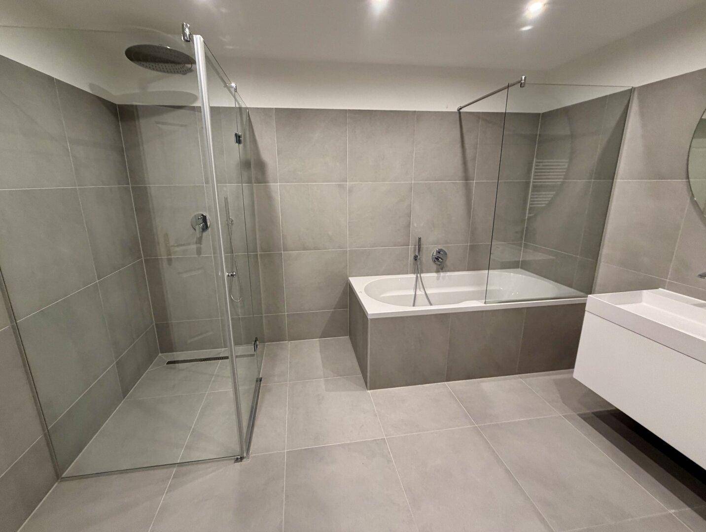 Elegantes Badezimmer mit großer Dusche, Badewanne und modernen Armaturen.