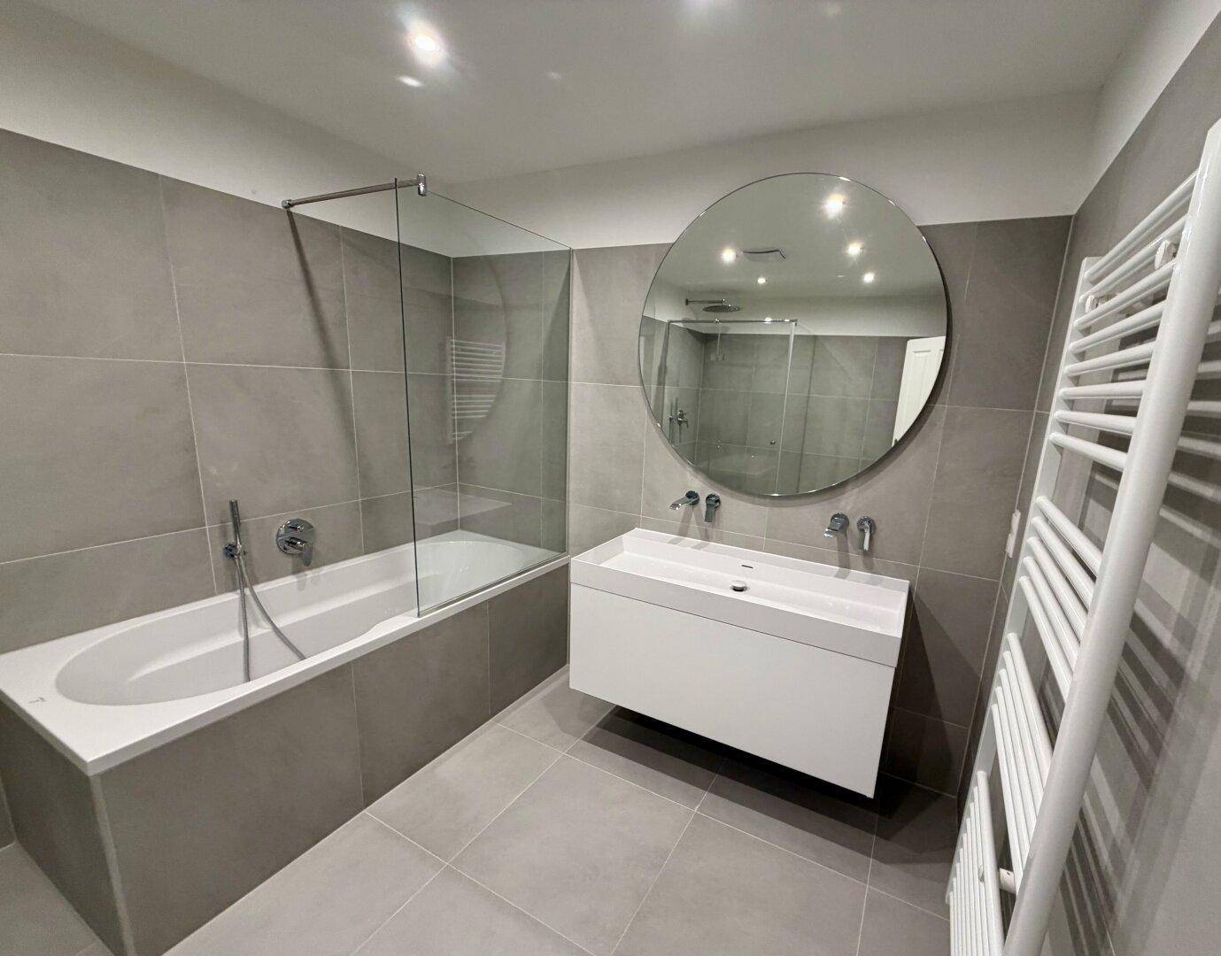 Modernes Badezimmer mit Badewanne, Dusche und schwebendem Waschtisch.