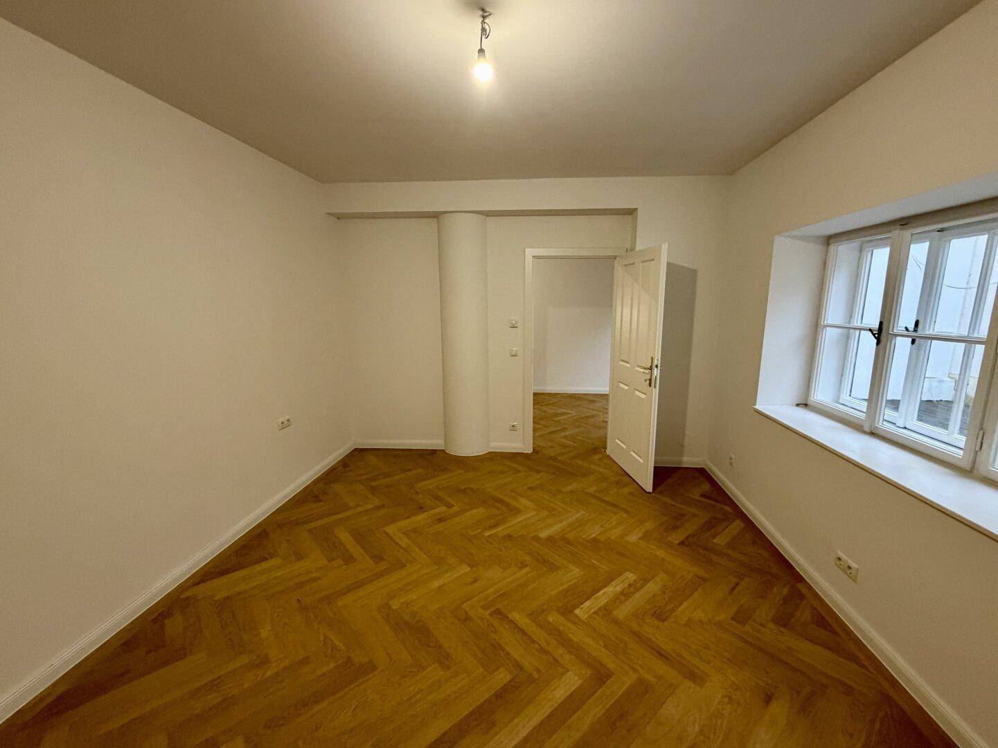 Helles Wohnzimmer mit frisch gestrichenen Wänden und elegantem Fischgrätparkett.