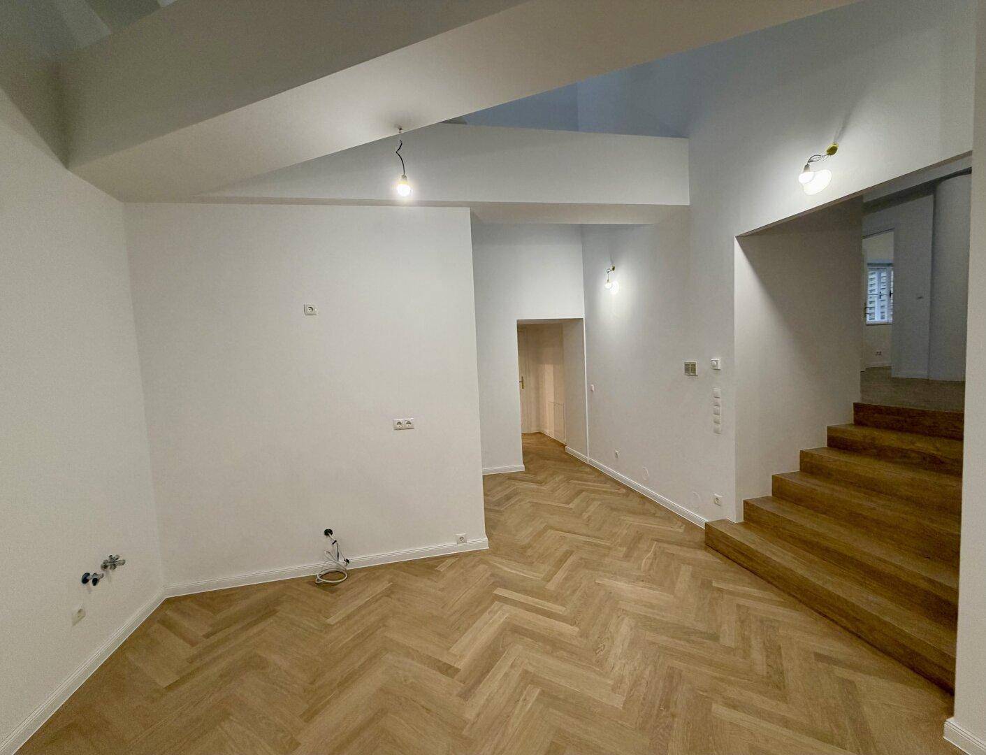 Offener Wohnbereich mit Holztreppe und Fischgrätparkett, ideal für modernes Wohnen.