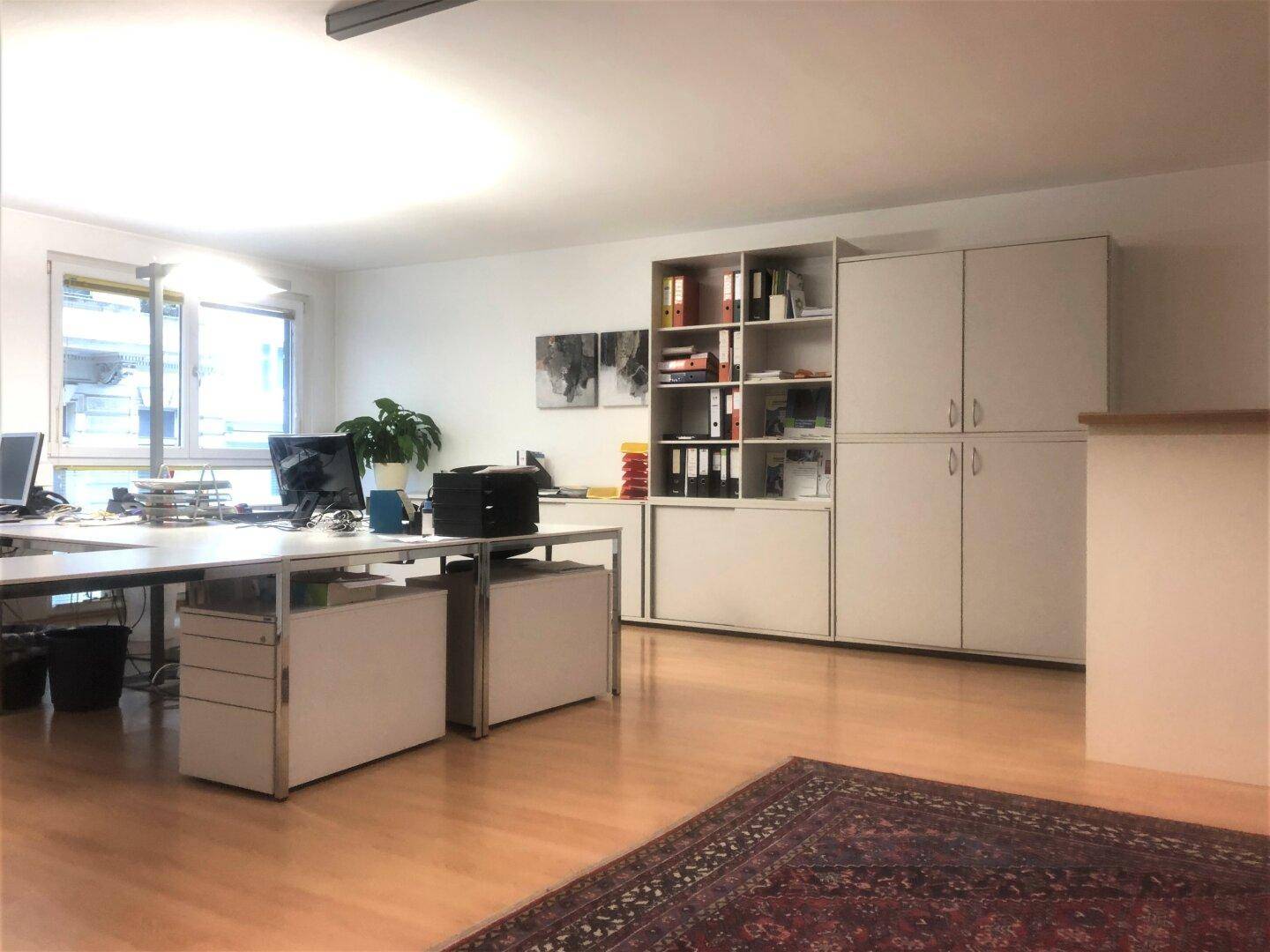 Großes Büro mit mehreren Arbeitsplätzen, Fenstern und umfangreichen Stauraummöglichkeiten, hell und funktional.