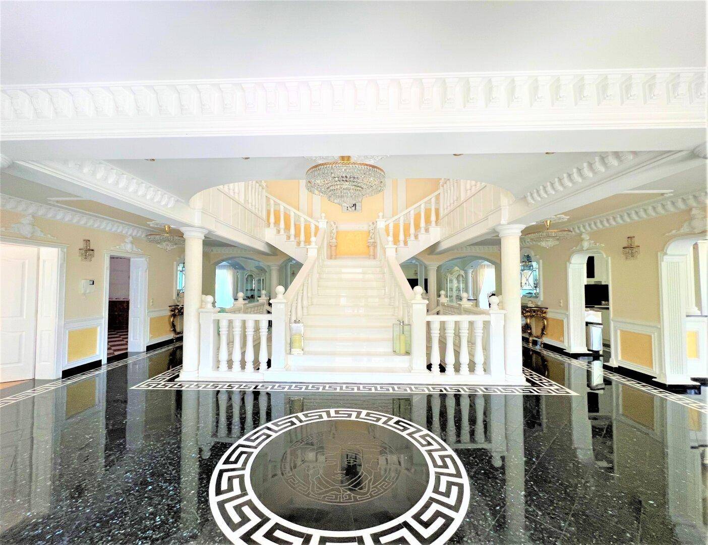Majestätische Eingangshalle mit einer symmetrischen Doppeltreppe und einem opulenten Kronleuchter.