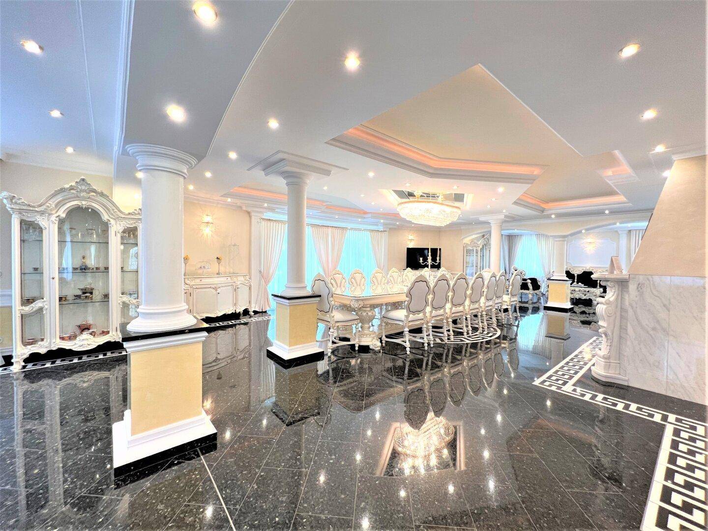 Eleganter Speisesaal mit einem langen Esstisch, luxuriösen Stühlen und glänzendem Granitboden.