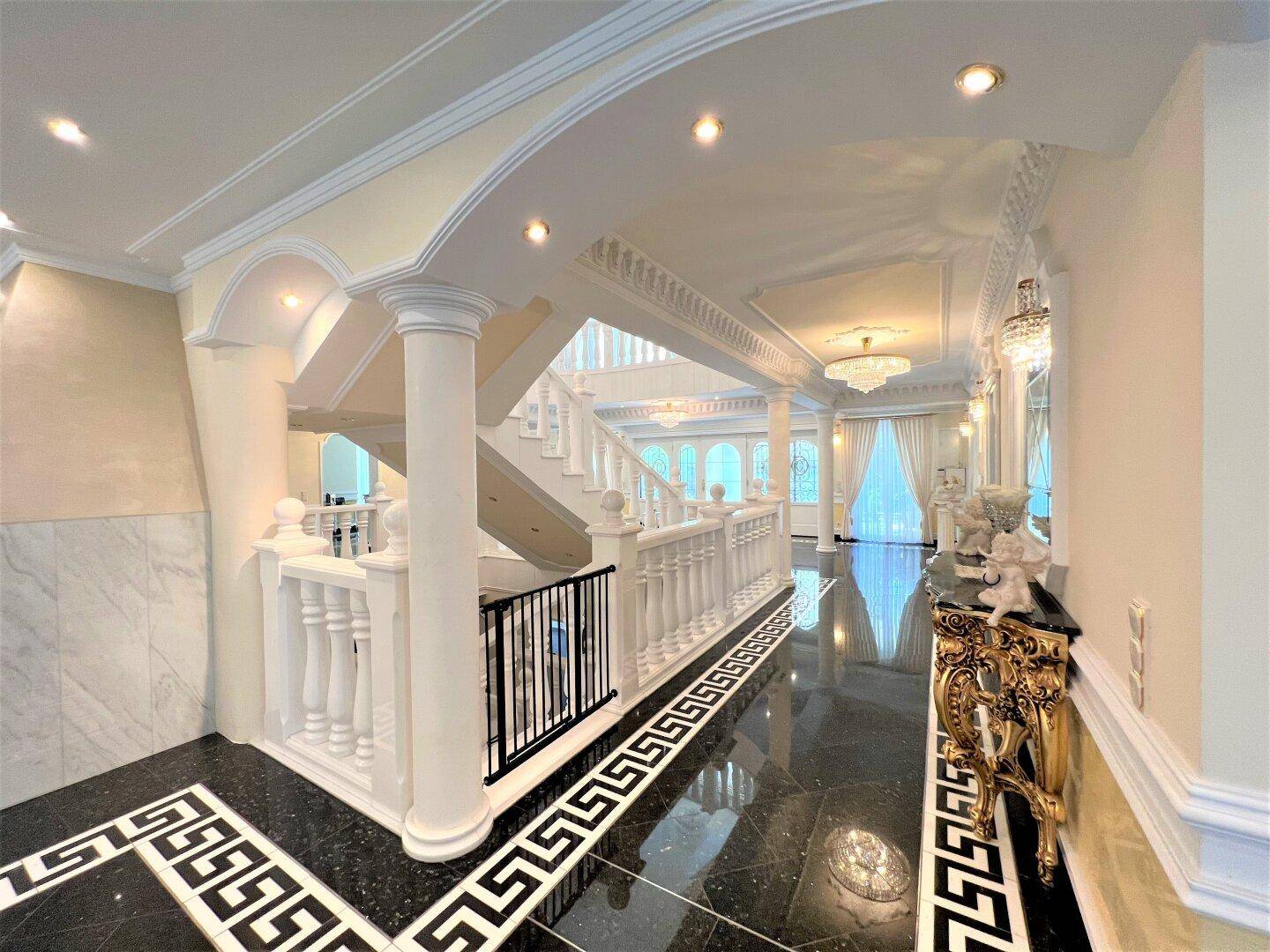 Eleganter Flur mit Blick auf die Treppe und den weitläufigen Wohn- und Essbereich.
