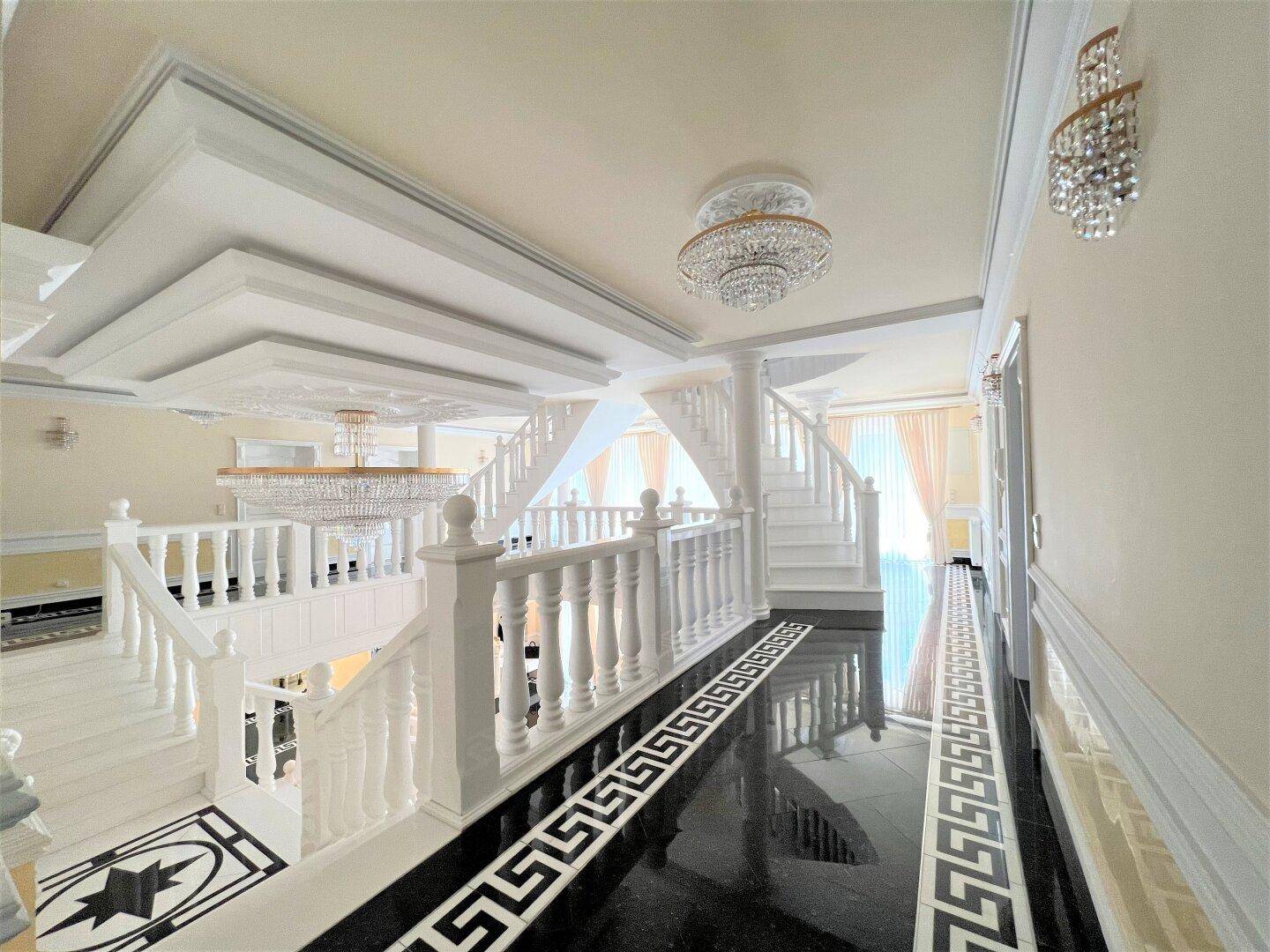 Oberer Bereich der Eingangshalle mit Blick auf die Treppe und den luxuriösen Wohnbereich im Hintergrund.