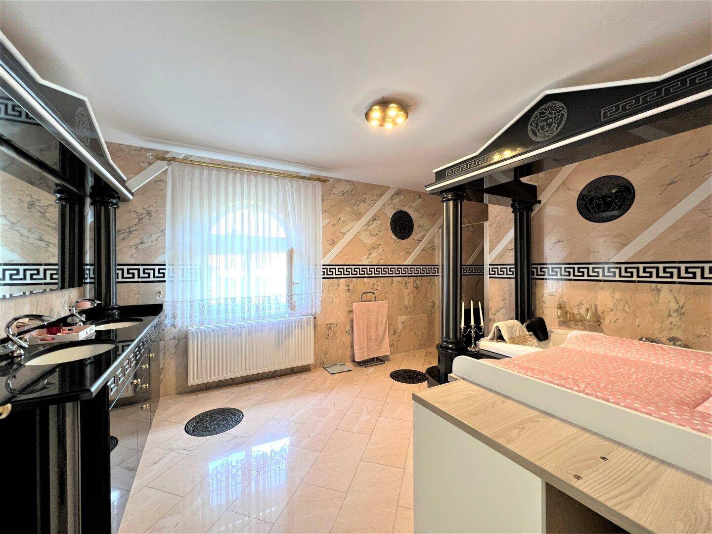 Luxuriöses Badezimmer mit Marmorfliesen, Doppelwaschbecken und Whirlpool.
