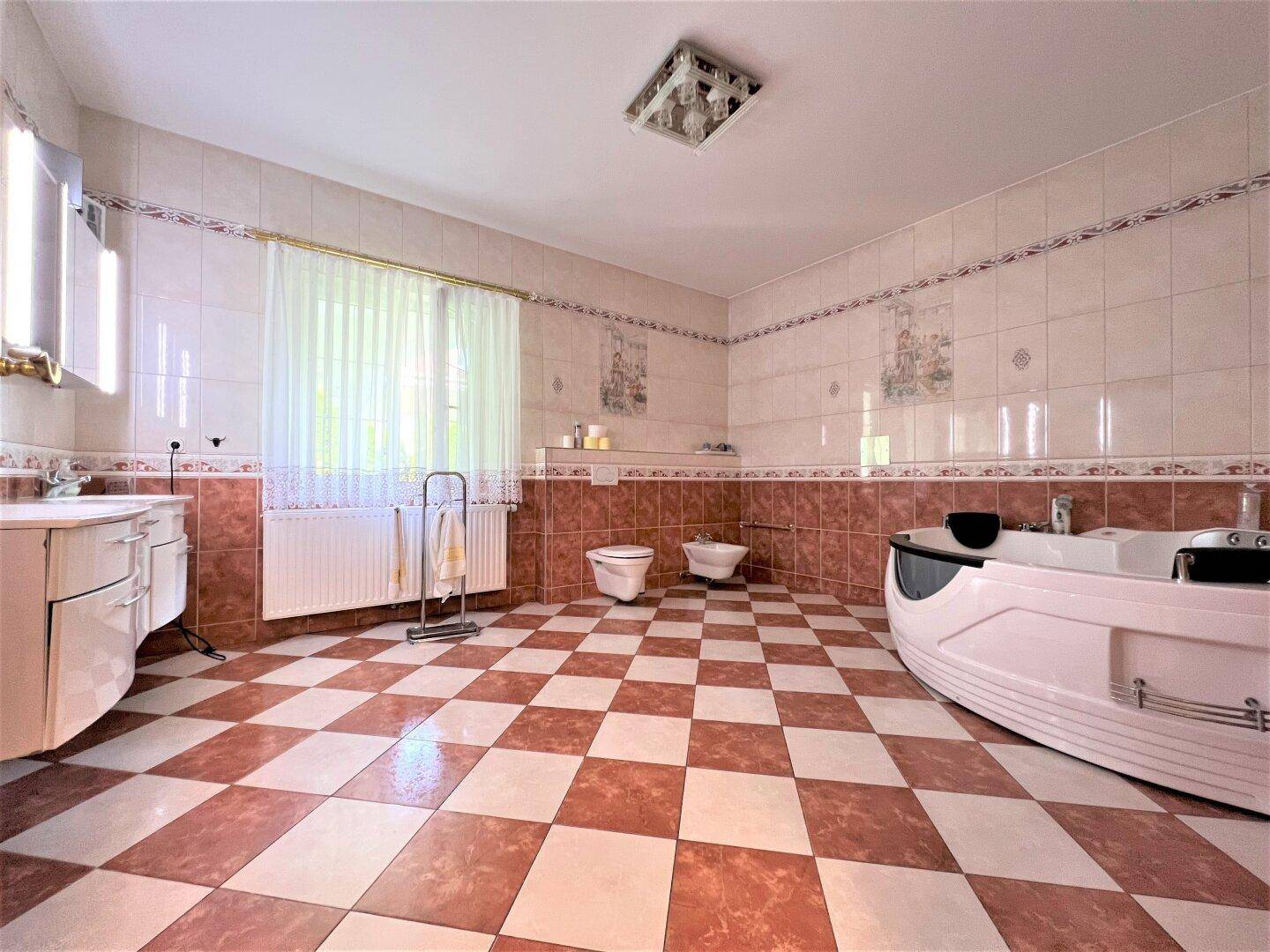 Geräumiges Badezimmer mit kariertem Fliesenboden und Whirlpool-Badewanne.