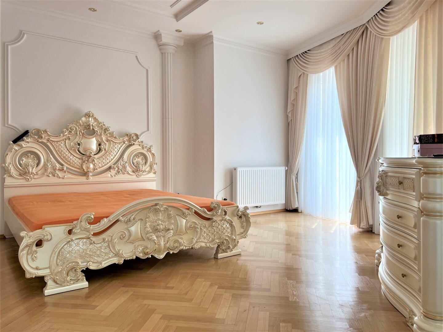 Elegantes Schlafzimmer mit kunstvollem Bettrahmen und Parkettboden.
