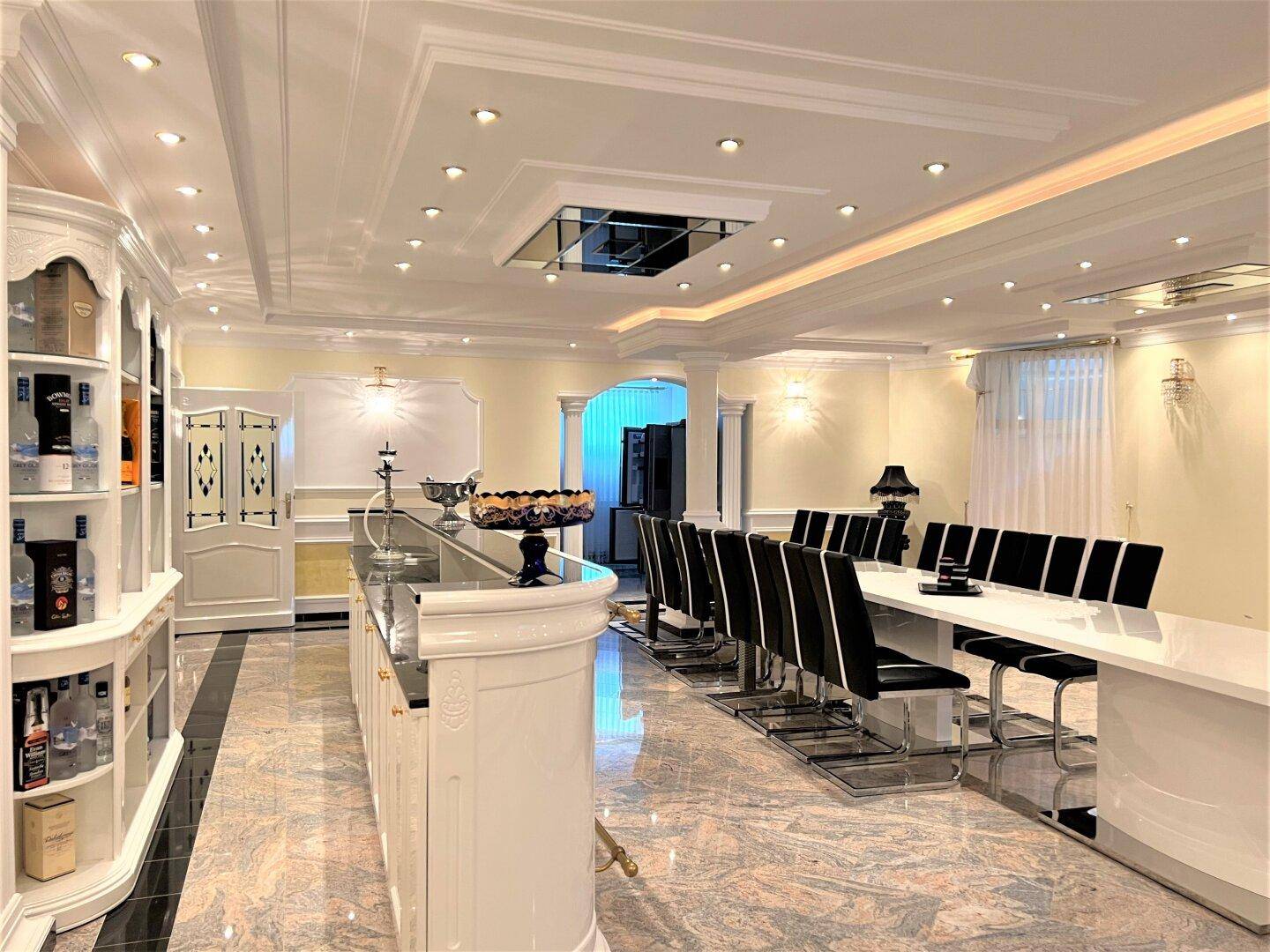 Eleganter Essbereich mit Marmorboden, langer Tafel und integrierter Bar.