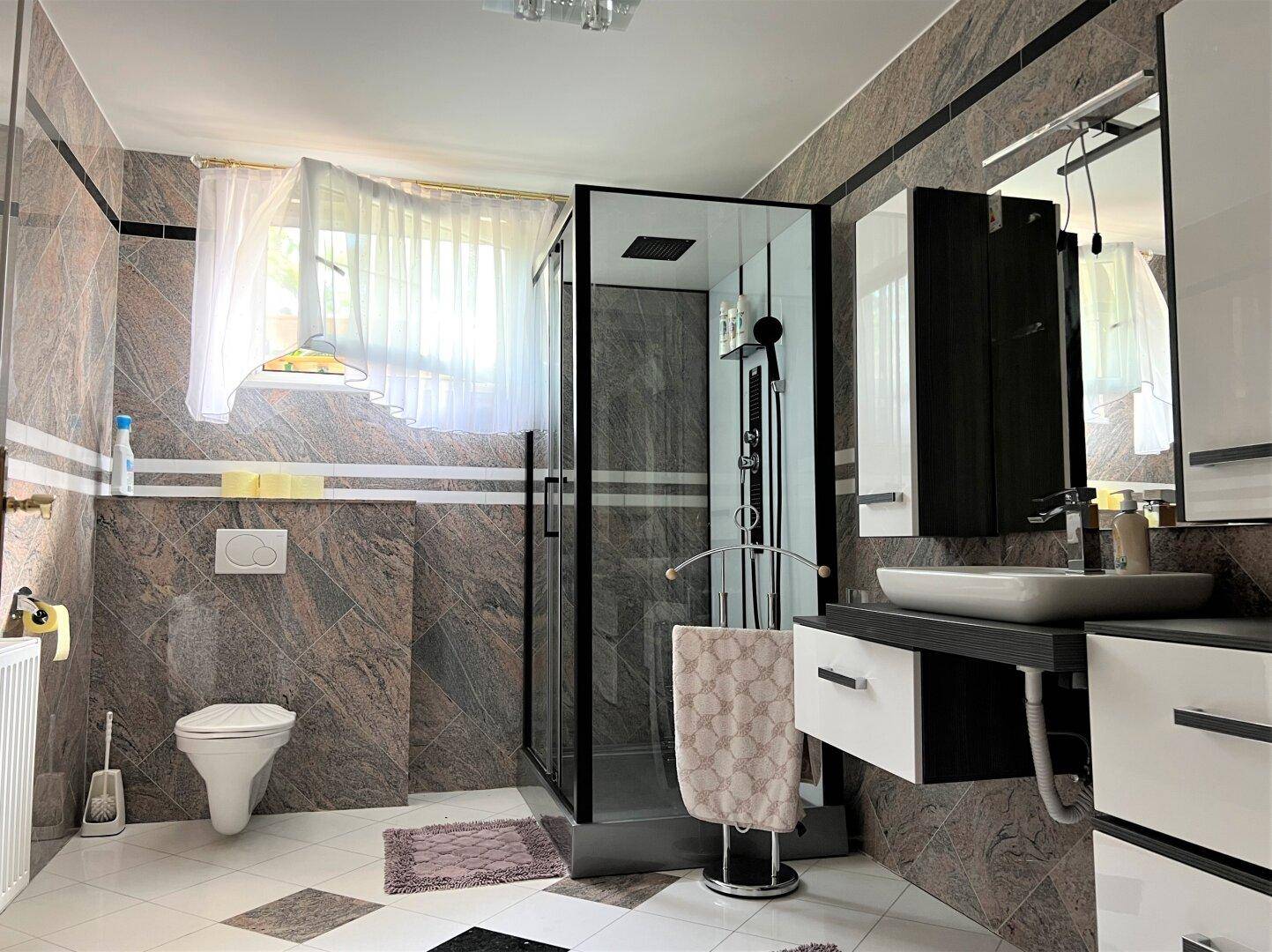 Modernes Badezimmer mit Duschkabine, Wand-WC und Marmorfliesen.