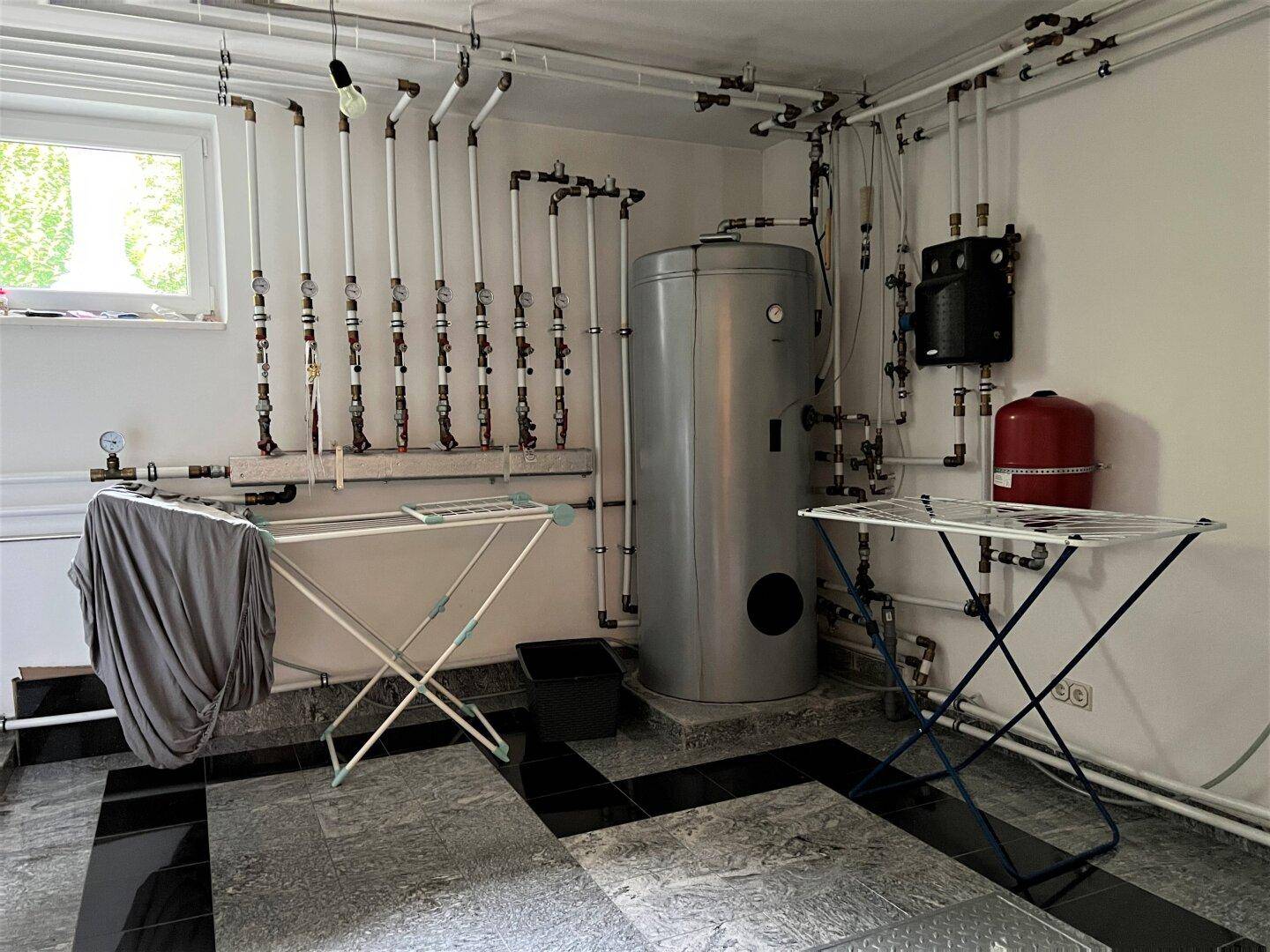 Heizungsraum mit Warmwasserspeicher und Wäscheständern.