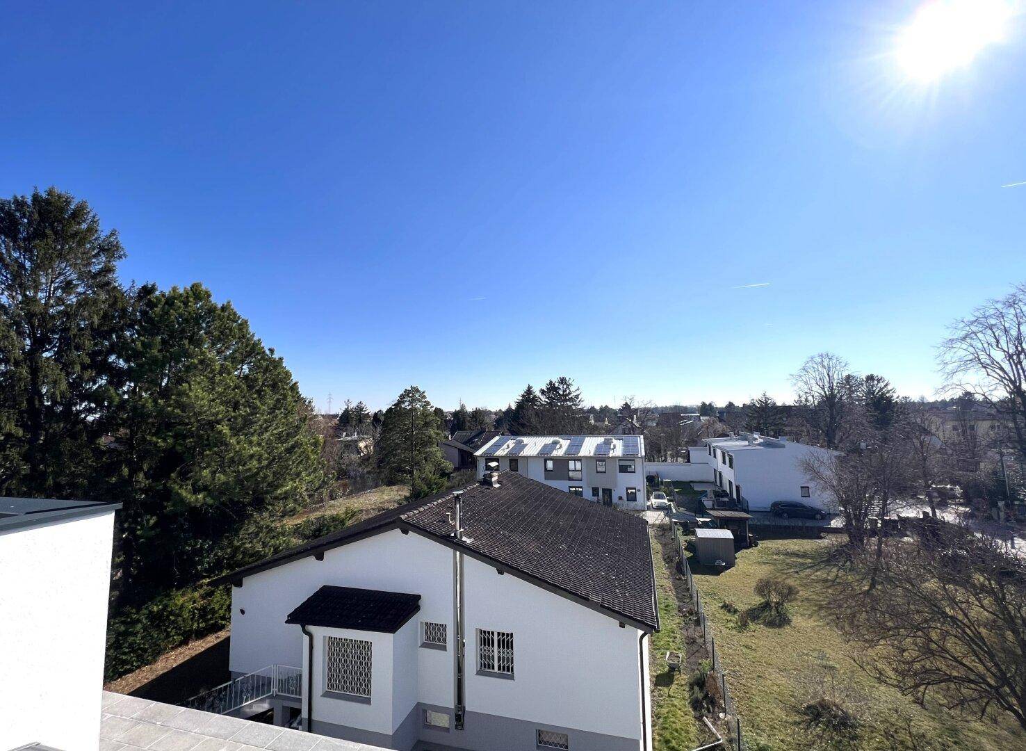 Weitläufiger Blick über die Wohngegend mit Häusern und viel Grün unter klarem blauem Himmel.