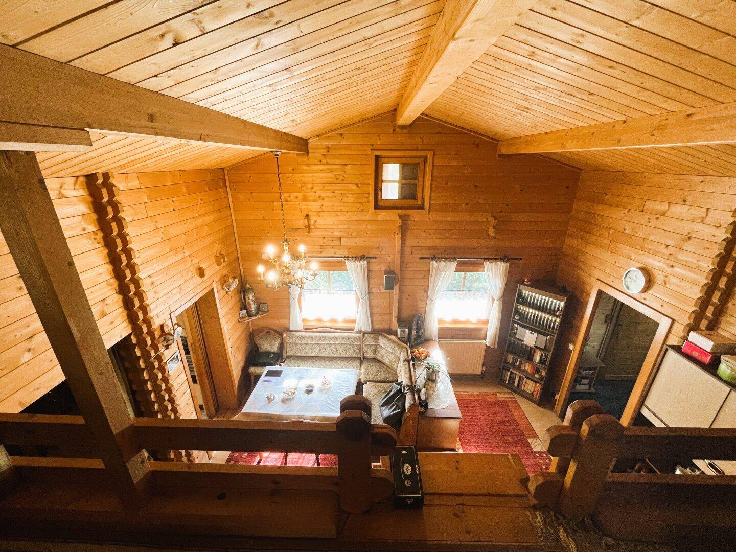 Blick vom Dachgeschoss auf den offenen Wohn- und Essbereich mit hohen Holzdecken.