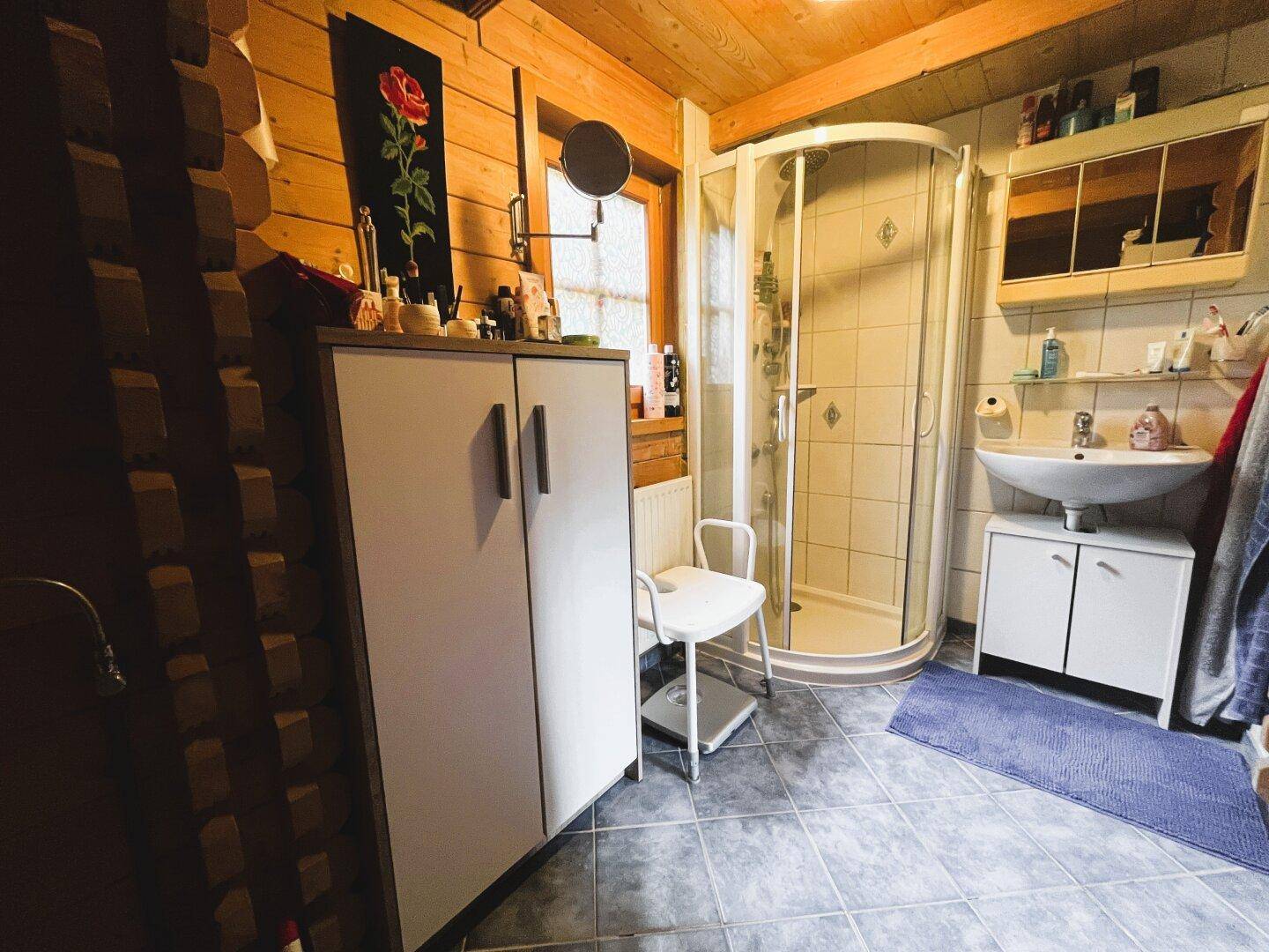 Badezimmer mit Duschkabine, Waschbecken, Spiegelschrank und Fliesenboden.