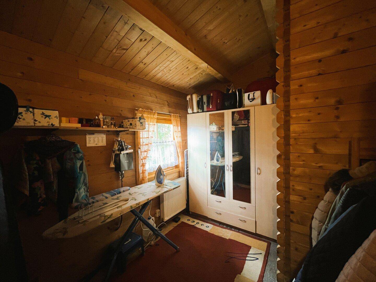 Praktischer Abstellraum mit Bügelbrett, Kleiderschrank und Fenster.