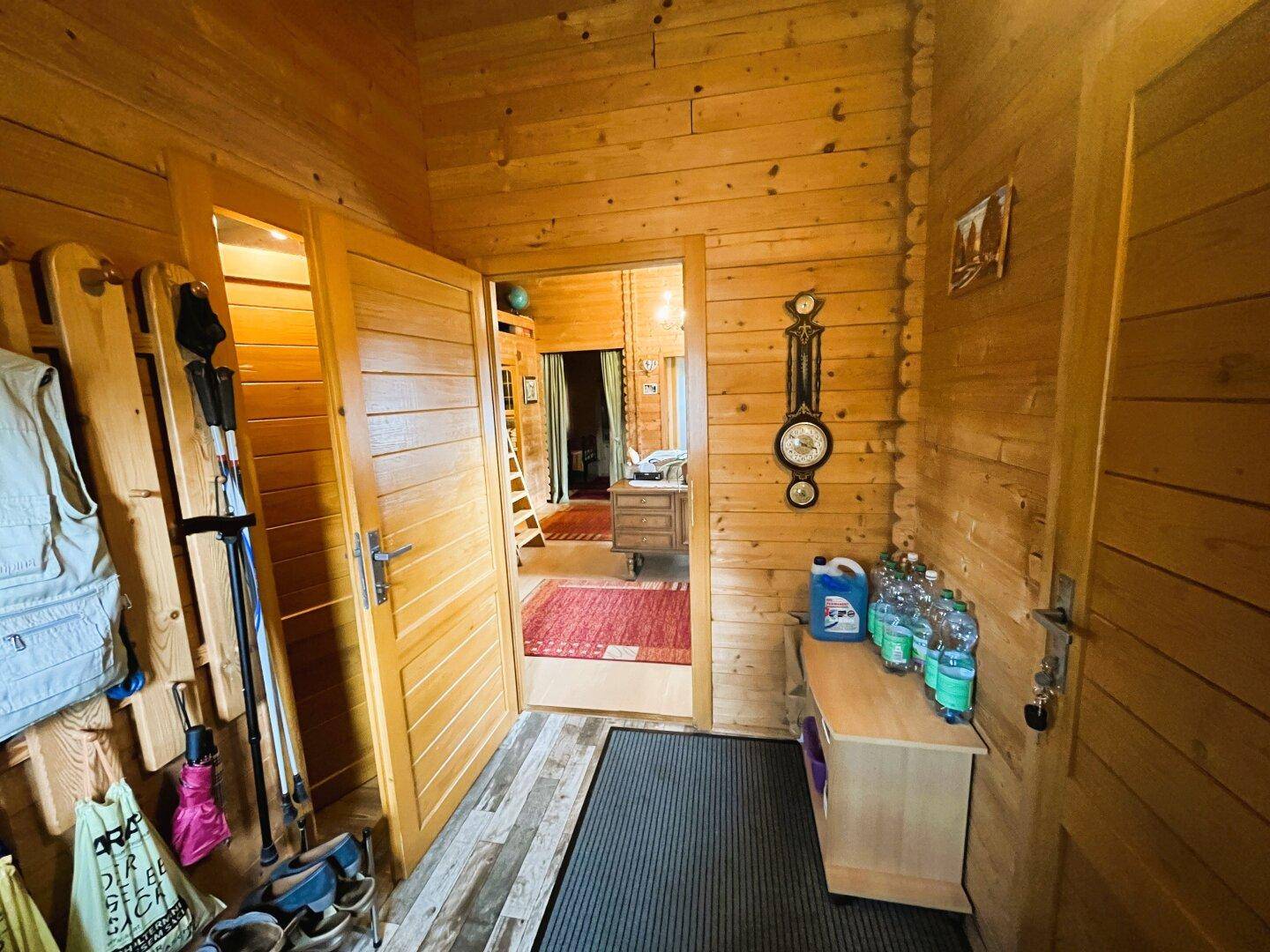 Eingangsbereich mit Holzwänden, Garderobe und Zugang zu weiteren Räumen.