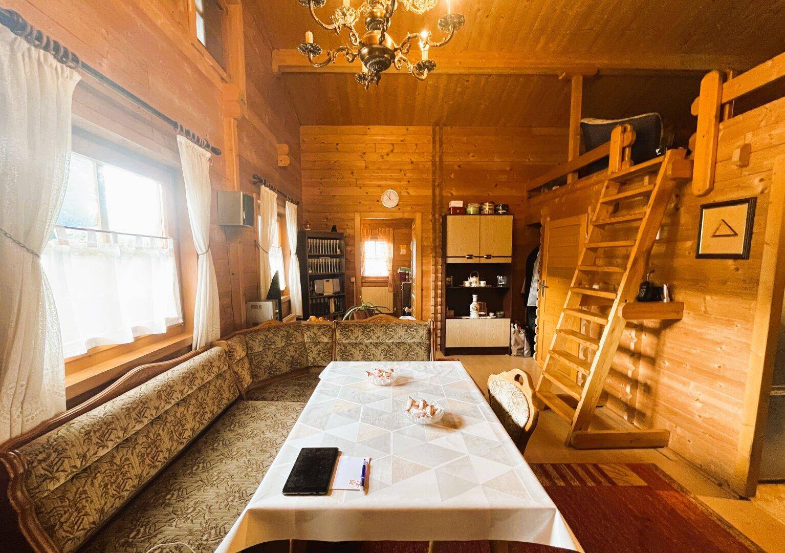 Gemütlicher Wohn- und Essbereich im Holzhaus mit traditionellen Möbeln und Holzwänden.