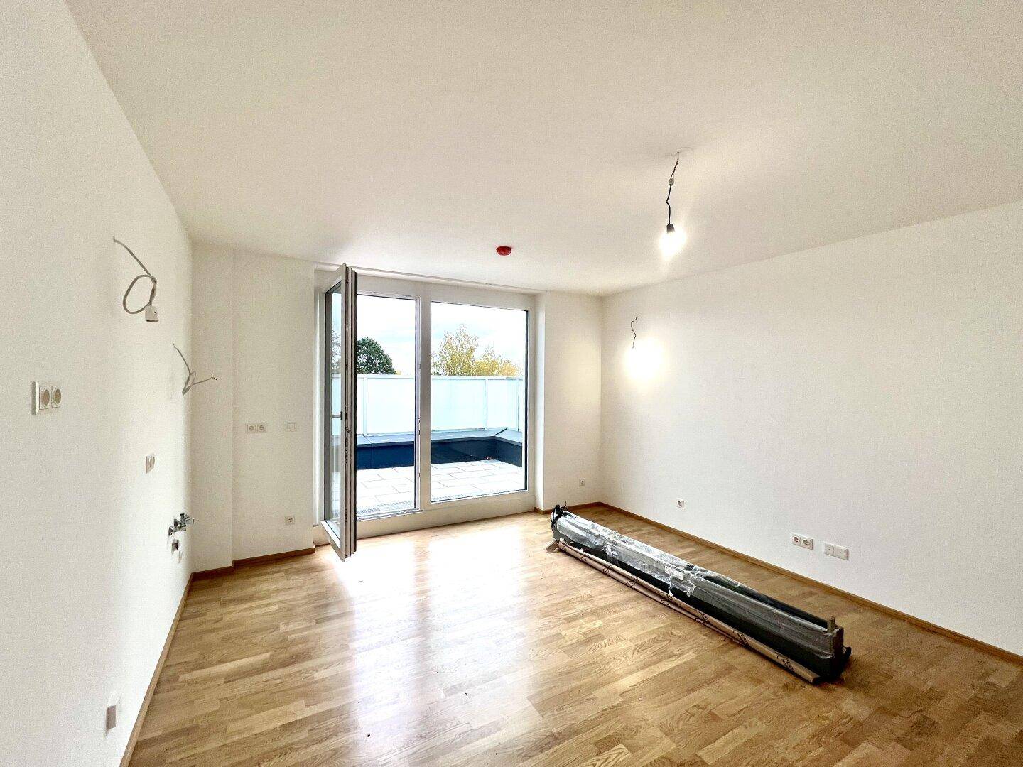 Lichtdurchflutetes Zimmer mit Parkettboden und breiter Terrassentür, bereit für die Einrichtung.