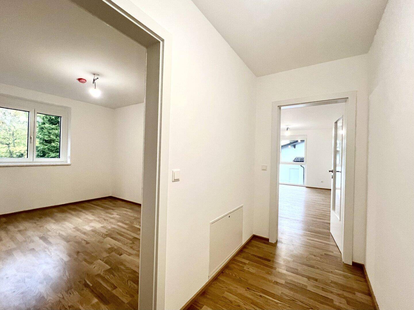 Heller Flur mit Parkettboden und Türen, die zu weiteren Zimmern und einem Fenster führen.