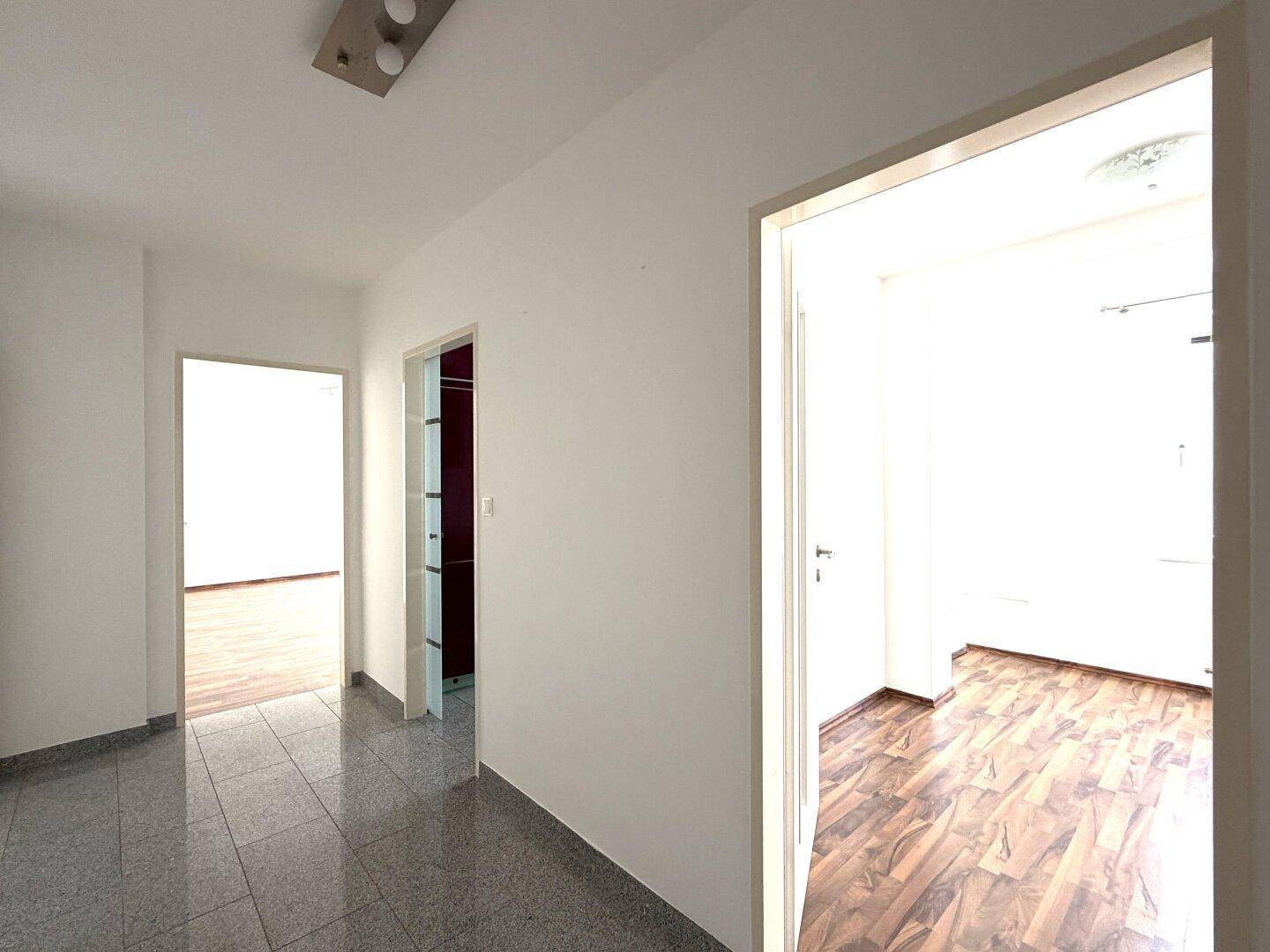 Heller Flur mit Fliesenboden und Zugang zu verschiedenen Zimmern der Wohnung.