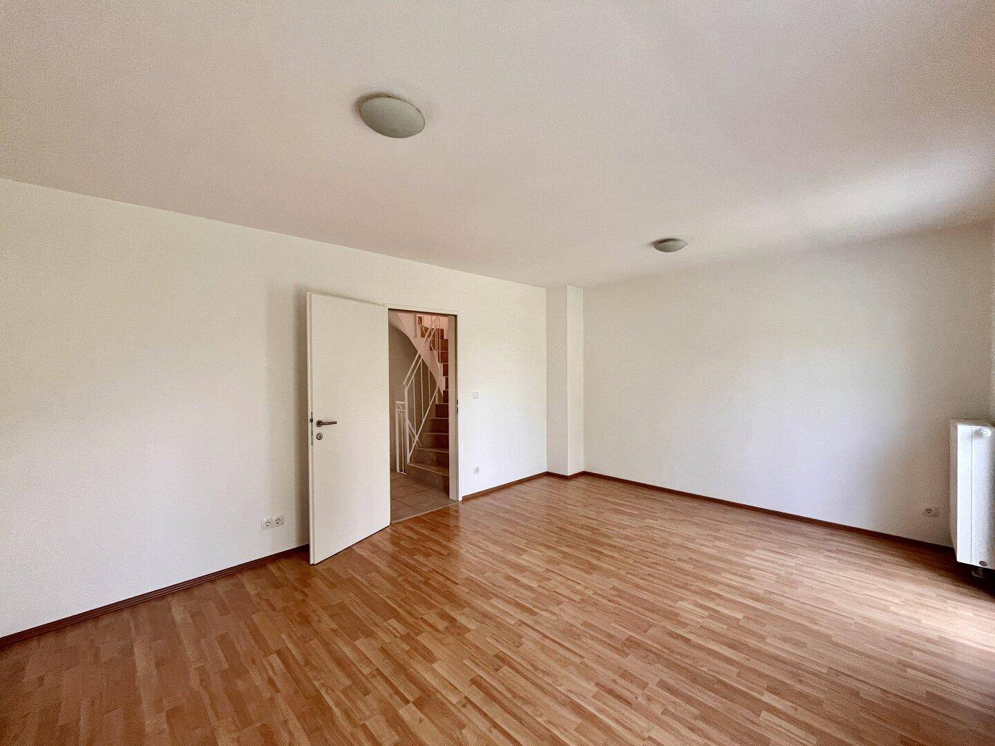 Geräumiges Zimmer mit Holzboden und Zugang zur Treppe, ideal für Schlaf- oder Arbeitsbereich.