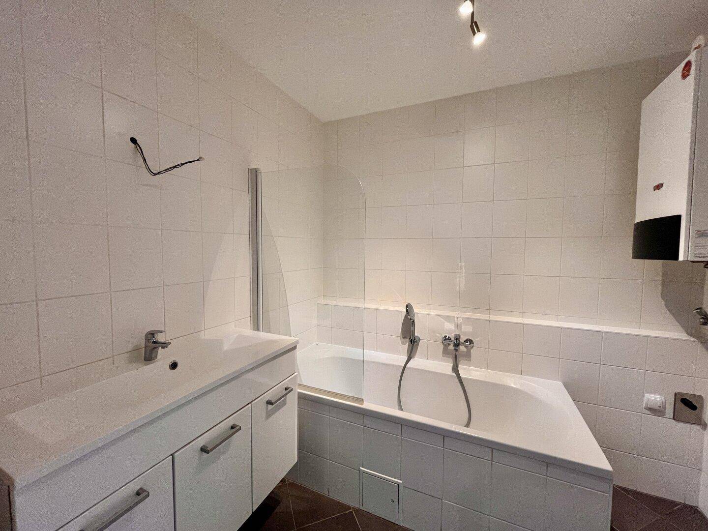 Modernes Badezimmer mit Badewanne, Waschtisch und weißen Fliesen.
