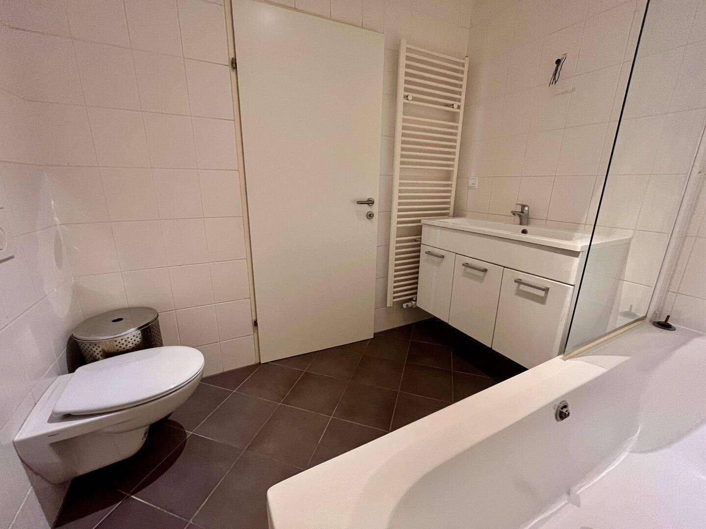 Badezimmer mit WC, Waschtisch, Badewanne und beheiztem Handtuchhalter.