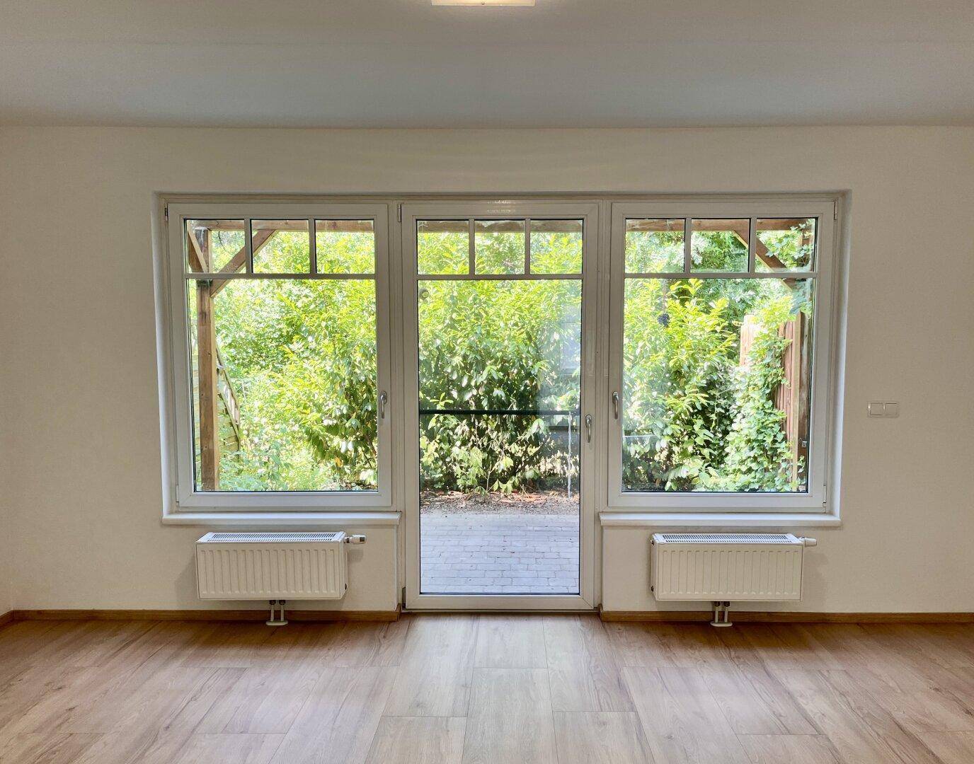 Große Fensterfront mit Terrassentür bietet einen schönen Blick ins Grüne und viel Tageslicht.