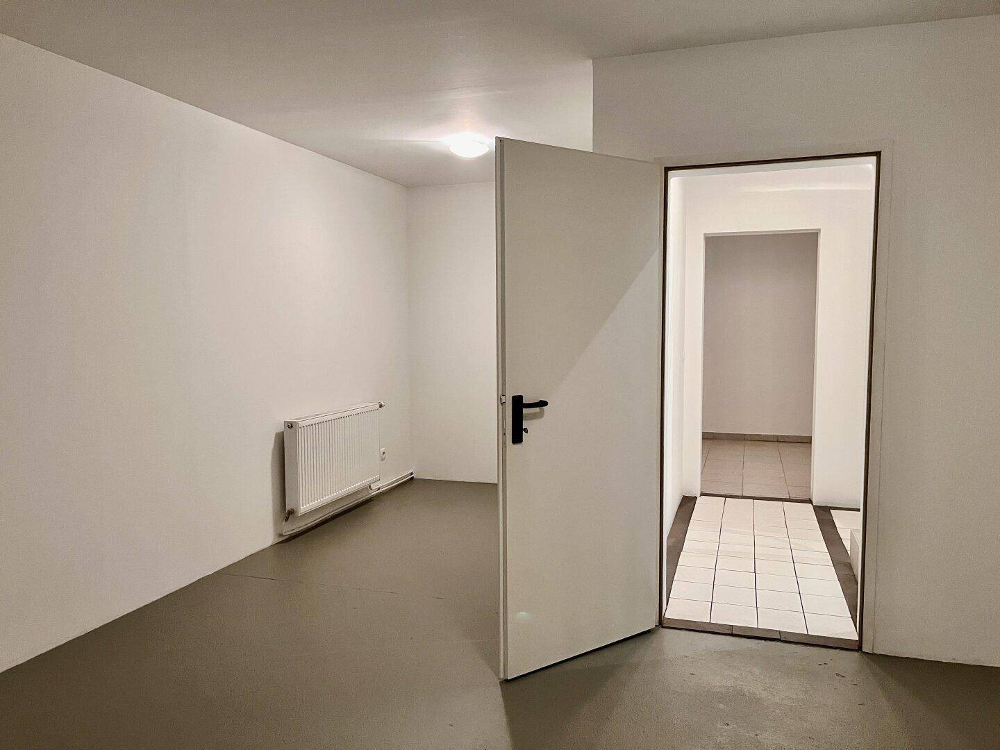 Geräumiger Kellerraum mit grauem Boden und Zugang zu weiteren Räumlichkeiten im Untergeschoss.