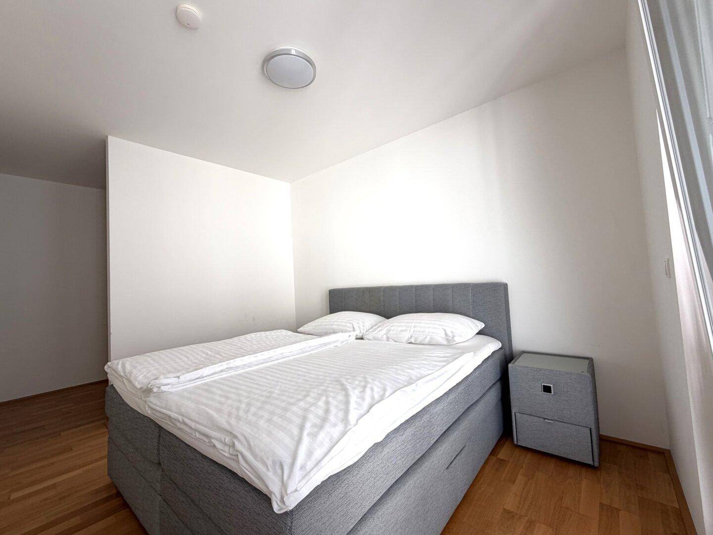 Ruhiges Schlafzimmer mit komfortablem Bett und einem Nachttisch, ideal zum Entspannen.