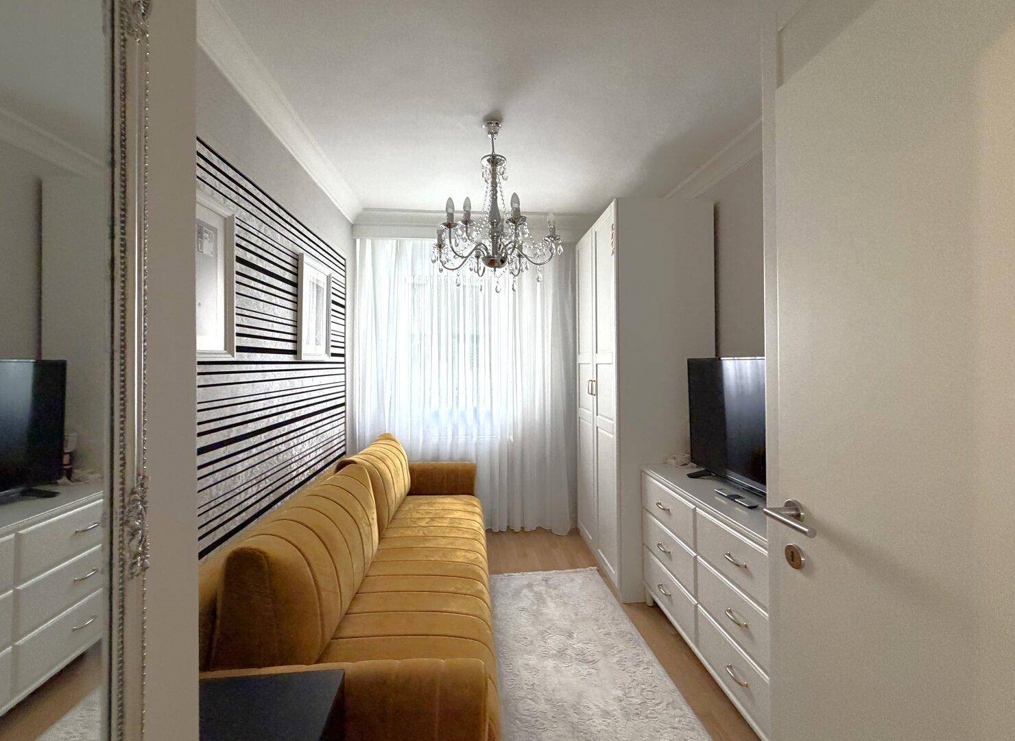 Kleines Zimmer mit gelbem Sofa, weißem Schrank und dekorativer schwarz-weiß gestreifter Wandgestaltung.