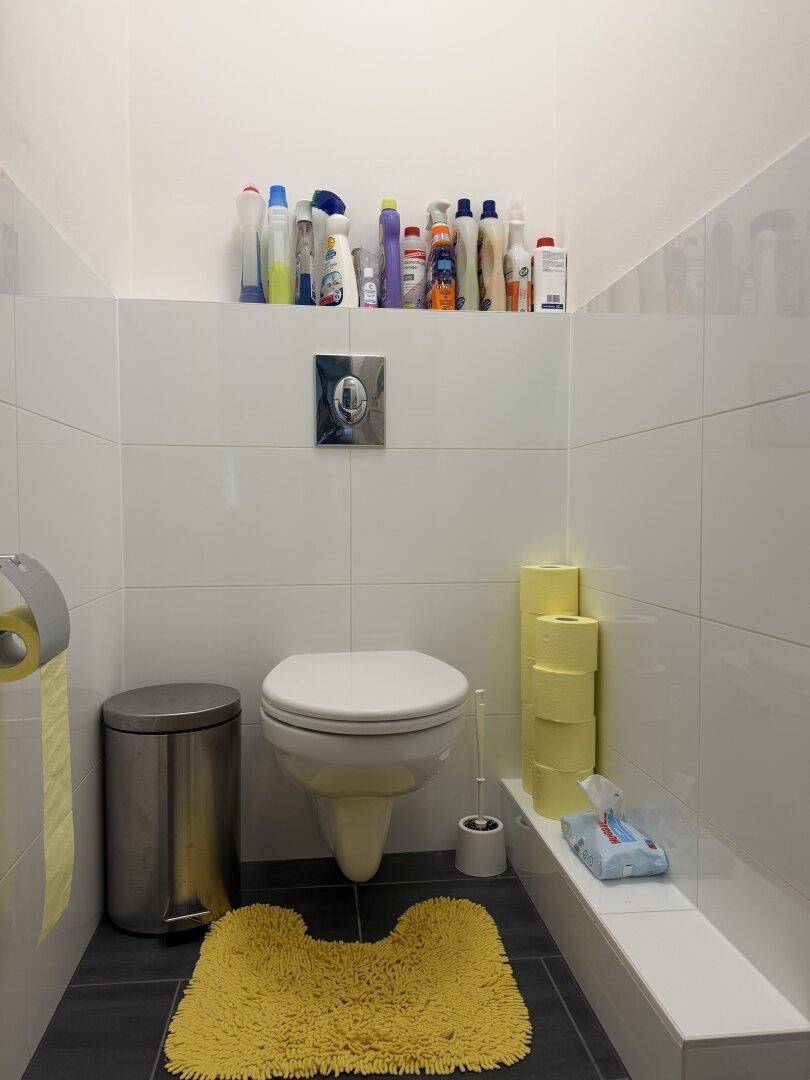 Separates WC mit wandhängender Toilette und weißen Fliesen.