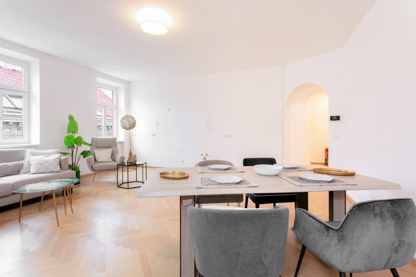 Eleganter Essbereich mit modernem Tisch und Stühlen, verbunden mit dem Wohnbereich durch einen Bogen.