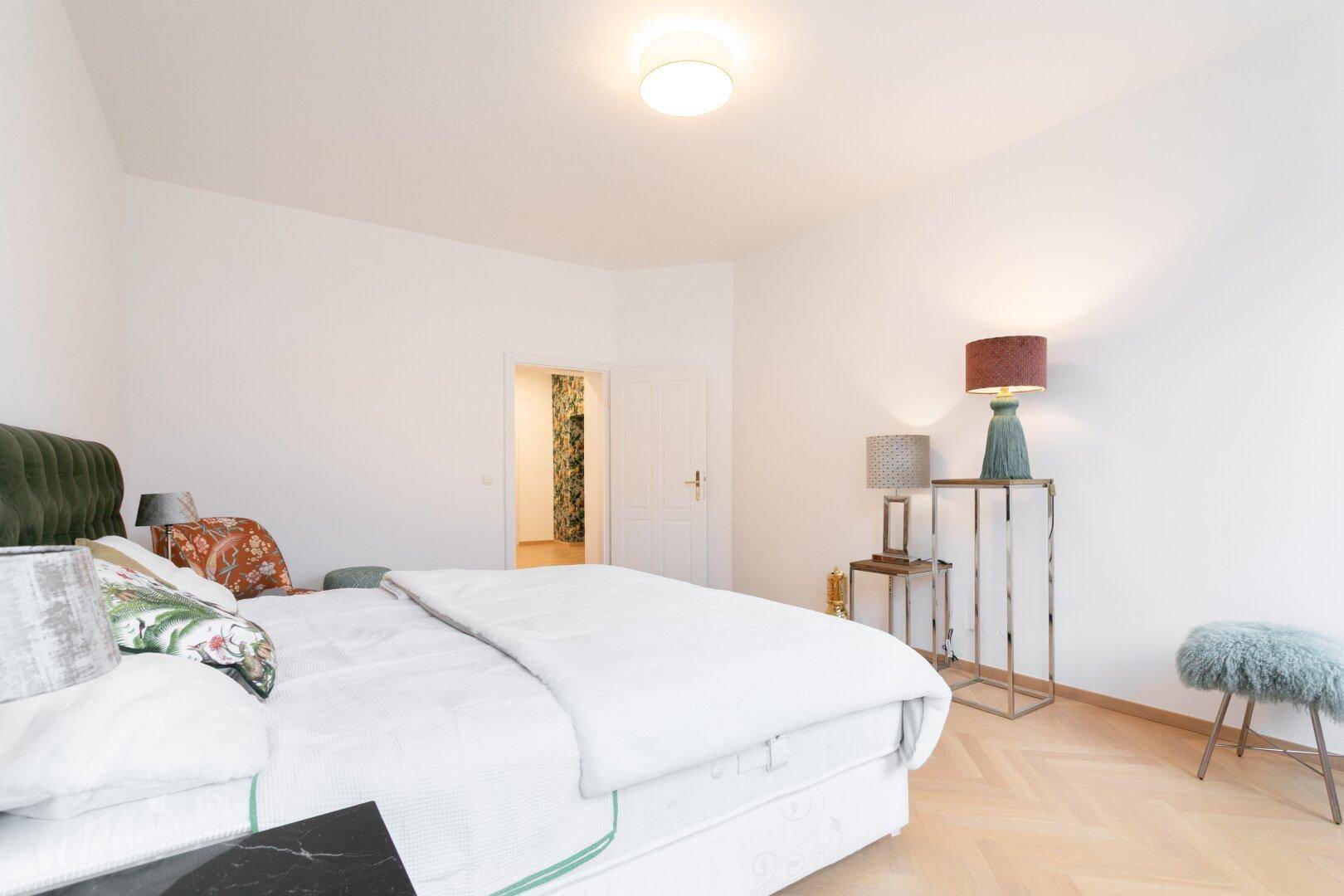 Schlafzimmer mit Blick auf den Flur, ausgestattet mit eleganten Nachttischen und Lampen.