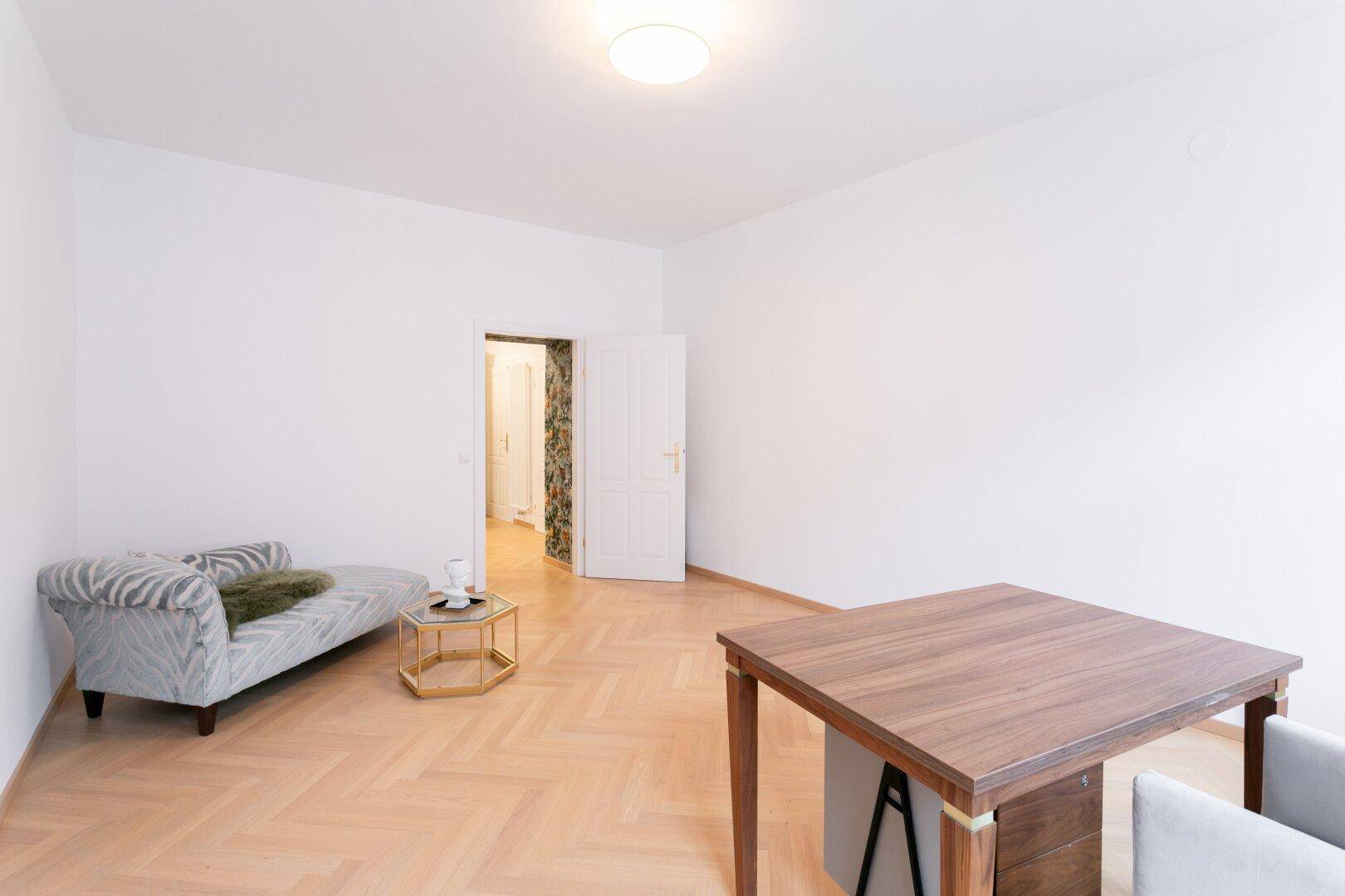 Arbeitszimmer mit Schreibtisch und einer Chaiselongue, verbunden mit dem Flur.