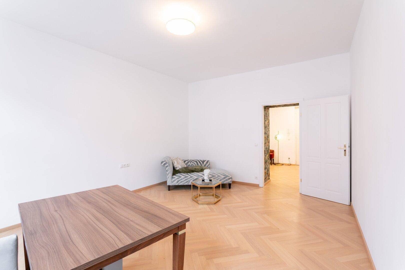 Geräumiges Arbeitszimmer mit Fischgrätparkett und Blick auf den Eingangsbereich.
