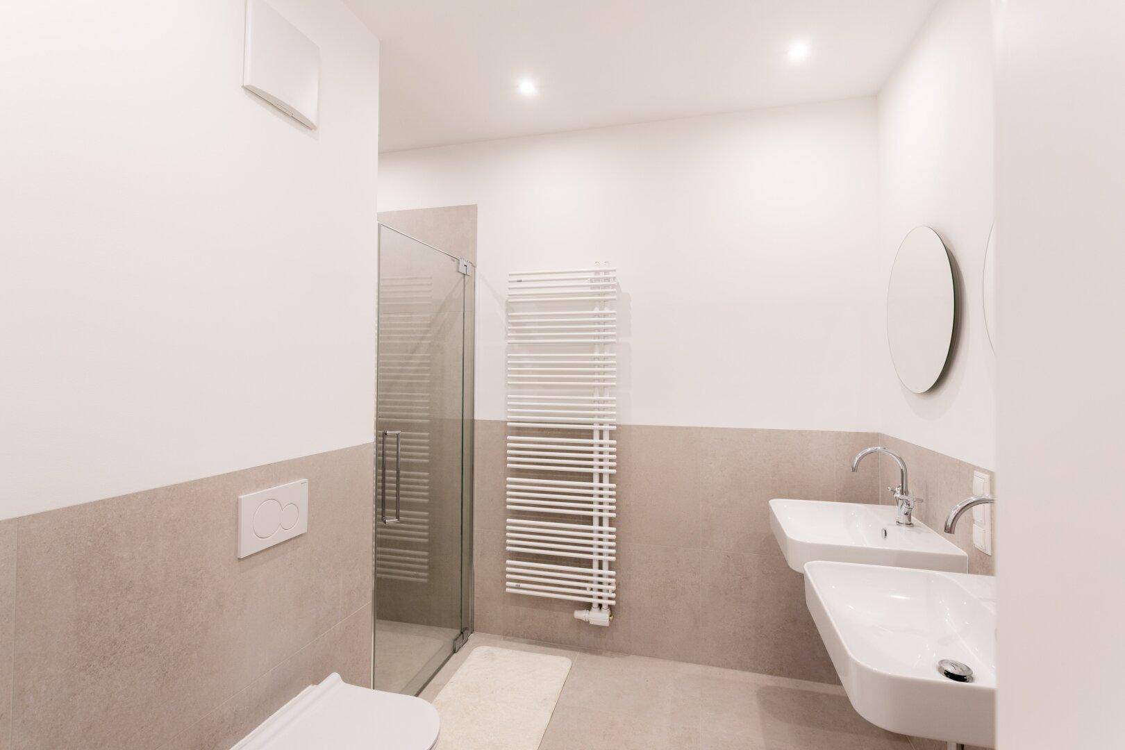 Zeitgemäßes Badezimmer mit Duschkabine, Doppelwaschbecken und Wand-WC.