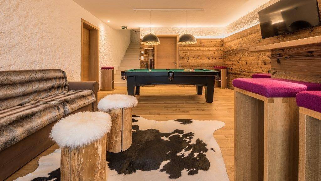Spielzimmer mit Billardtisch, Sitzgelegenheiten und Zugang zu einer Treppe.