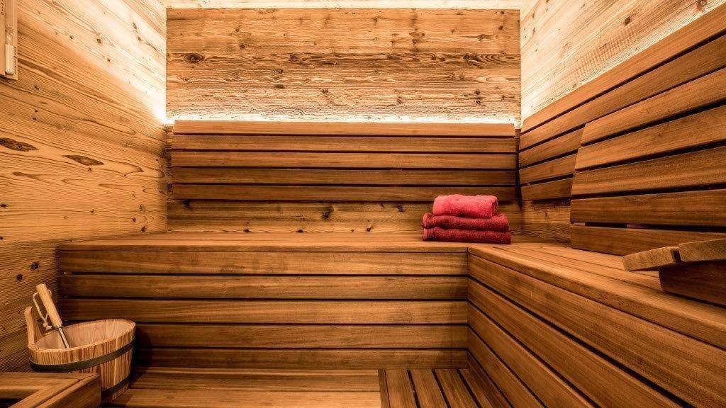Traditionelle Holzsauna mit mehreren Bänken und stimmungsvoller Beleuchtung.