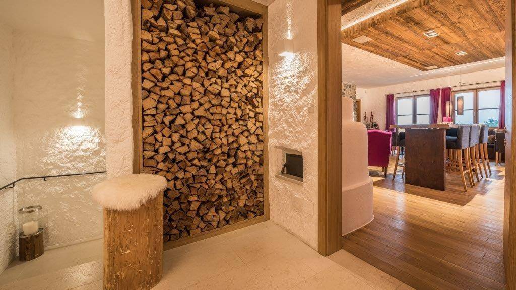 Eingangsbereich mit dekorativer Holzstapelwand und Blick in den offenen Wohnbereich.