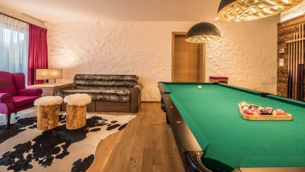 Geräumiger Unterhaltungsraum mit Billardtisch, bequemen Sofas und rustikalem Dekor.