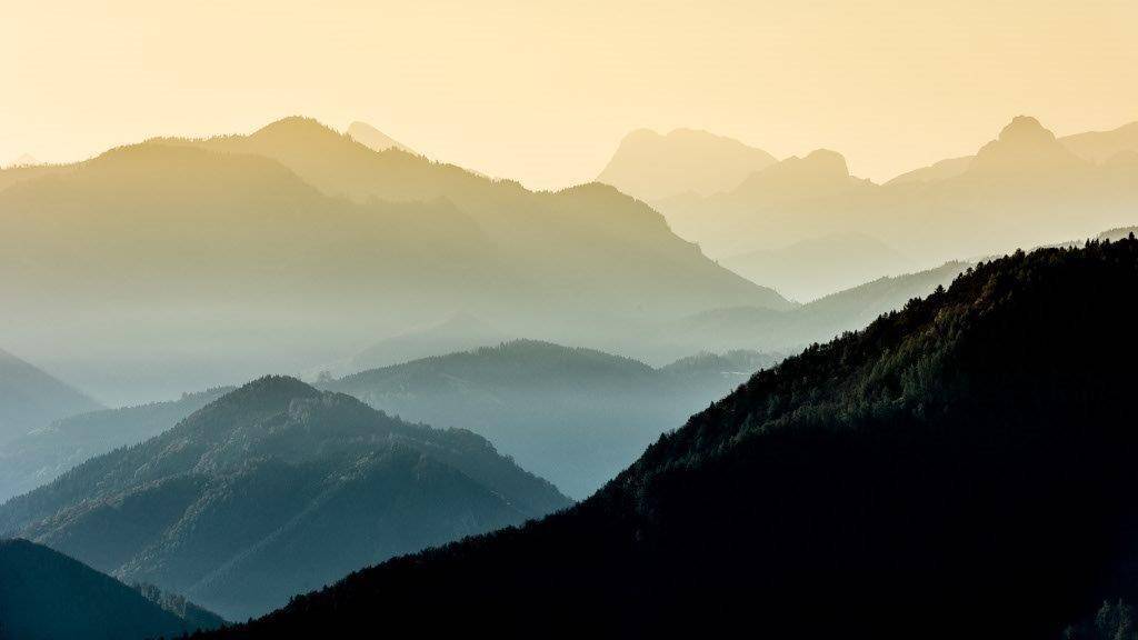 Abstrakte Berglandschaft bei Sonnenuntergang mit sanften Farbübergängen und Nebel.