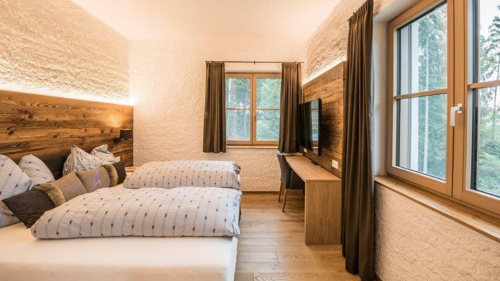 Gemütliches Schlafzimmer mit Holzbett, Schreibtisch und Blick ins Grüne.