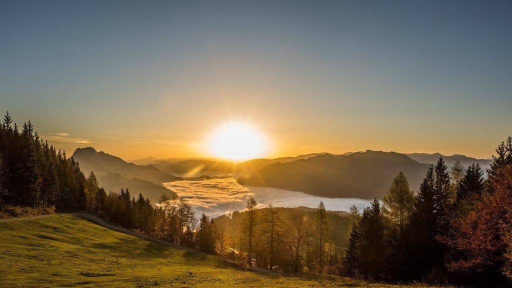 Atemberaubender Sonnenaufgang über den Bergen mit einem Meer aus Wolken im Tal.